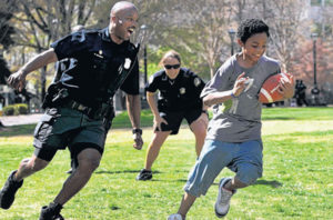 110319 Atlanta; Atlanta Police Department officer William Dorsey, left, chases Brandin McNair, 11, of Atlanta, during a football game with the APD officers against the kids at an APD Expo at Woodruff Park Saturday morning in Atlanta, Ga., March 19, 2011. Dorsey is part of the Atlanta Police Department Community Oriented Policing Unit. APD is hitting the street with a new community oriented policing unit that is to tie officers closer to neighborhoods instead of running from call to call. Jason Getz jgetz@ajc.com
